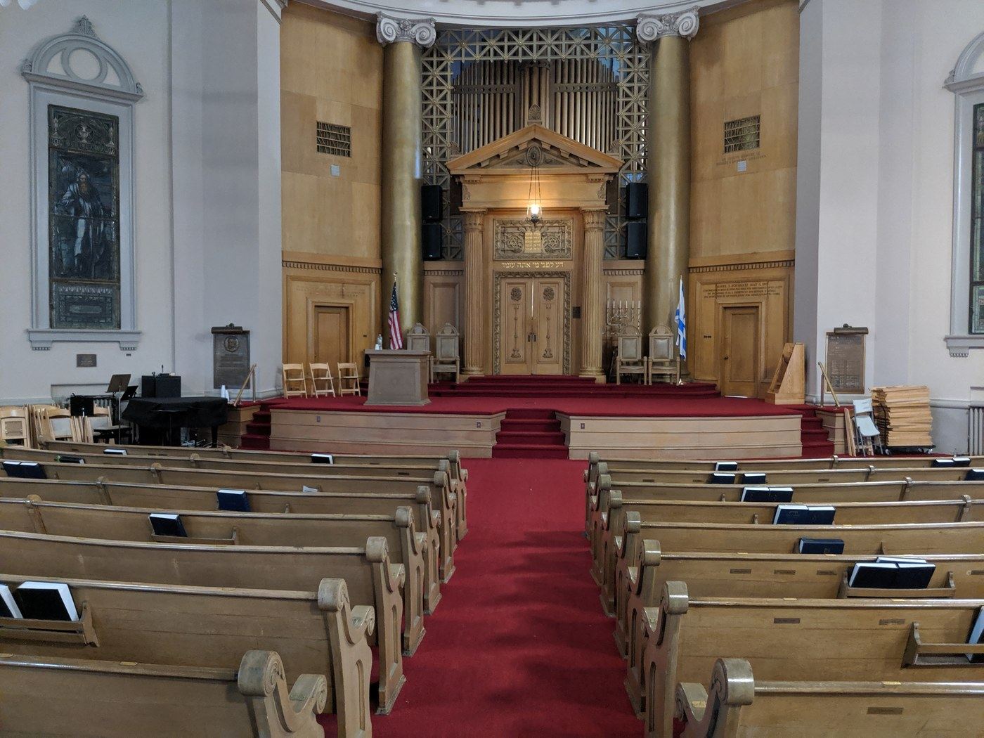 A grand synagogue sanctuary with gold columns and a red-carpeted aisle